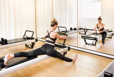 Bir kadın spor salonundaki yenilikçi yatağı kullanarak egzersiz yapıyor. Dikiz aynasından yansıyor. Sağlık ve zindelik kavramında.