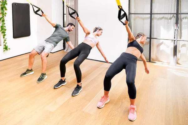 三名运动员进行牵引或悬挂力量拉力运动 以伸展和加强其核心肌肉 从而增加健康和健康概念的灵活性 — 图库照片
