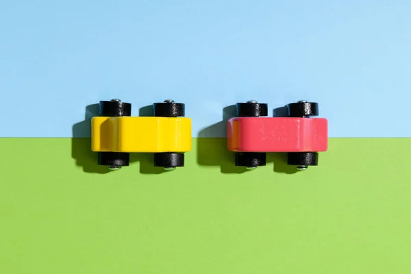 2台のカラフルな黄色と赤の木製のおもちゃの車が分割緑と青の背景に影で上から下に表示されます — ストック写真