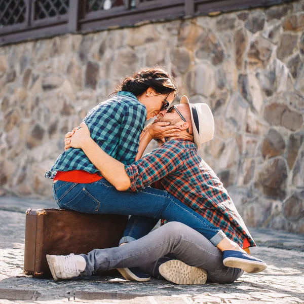 couple in love sitting on road with suitcase