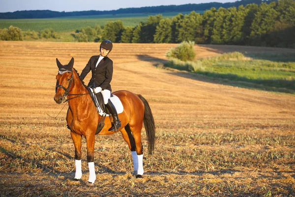 Chica joven montando caballo marrón con casco — Foto de Stock