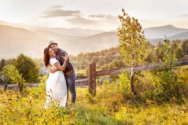 Loving para w górach w pobliżu ogrodzenia drewniane. — Zdjęcie stockowe