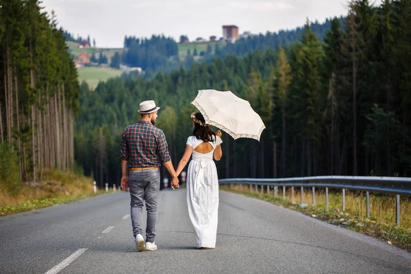 Любящая пара, идущая по дороге в лесу — стоковое фото