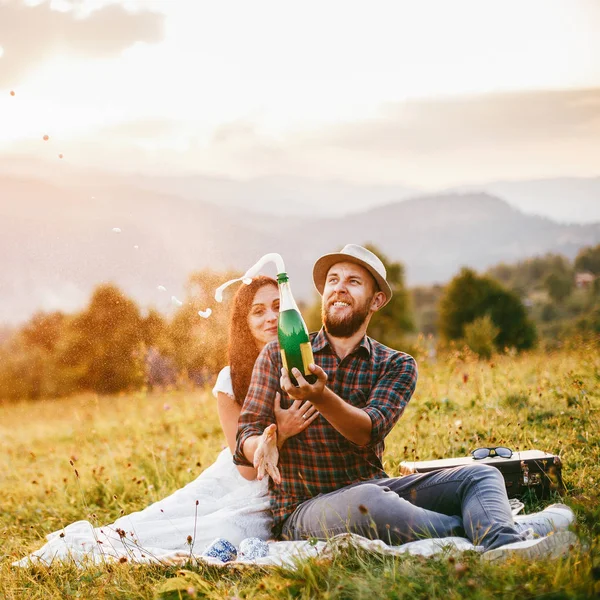 Liebespaar sitzt auf Plaid im Feld. Hintergrund Berge. — Stockfoto