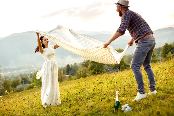 Para zakochanych, przygotowania do pikniku. rozprzestrzeniania się biały pled. — Zdjęcie stockowe