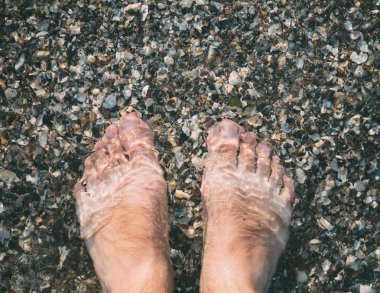Temiz su insan ayaklarda deniz çakıl.
