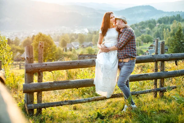 Älskande par i bergen nära ett staket i trä. — Stockfoto