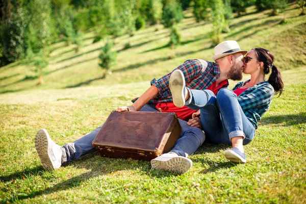 Verliefde paar in veld op picnic met koffer — Stockfoto