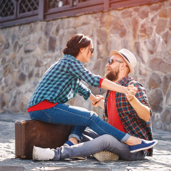 Para zakochanych siedzi na drodze z walizką — Zdjęcie stockowe