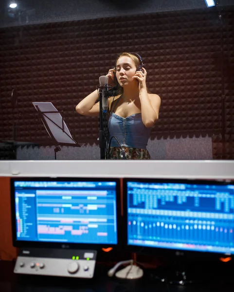 Girl singing in professional studio with mic, headphones and computers — Stock Photo, Image