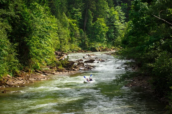 Два человека плывут на каноэ по горной реке — стоковое фото