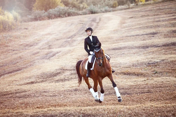 Mujer montando en caballo marrón usando casco — Foto de Stock