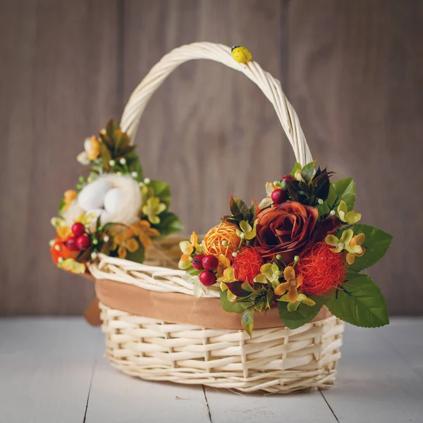 Basket with flowers to celebrate Easter on a wooden background — Stock Photo, Image