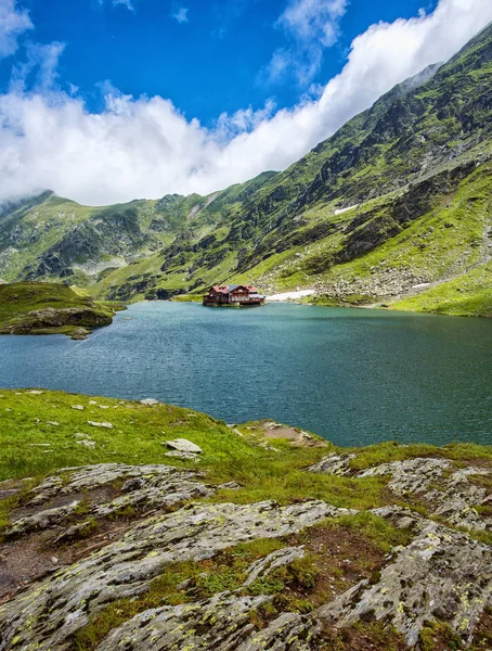 Dağ gölü. Göle kayaların arasında. Sahilde otel.
