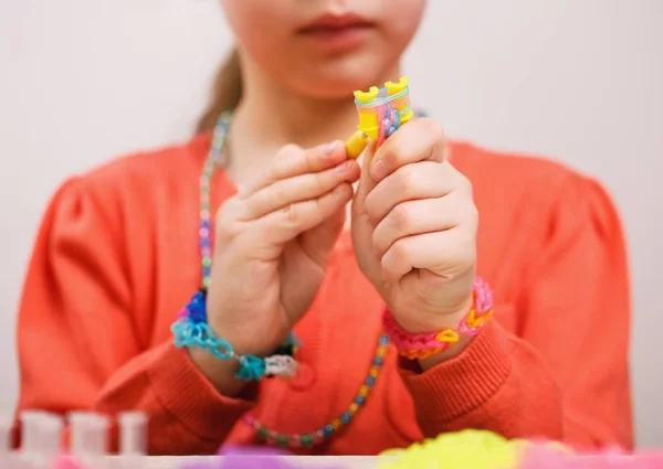 Faixas de borracha coloridas para tecer acessórios nas mãos de uma menina — Fotografia de Stock