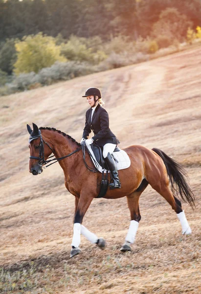 Mujer montando en caballo marrón usando casco — Foto de Stock