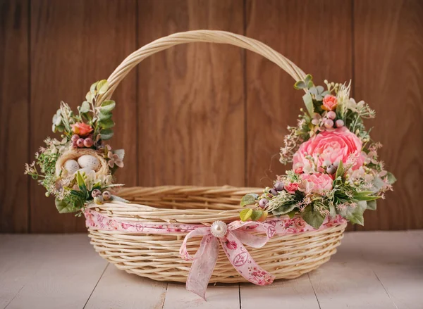 Корзина с цветами для празднования Пасхи на деревянном фоне — стоковое фото