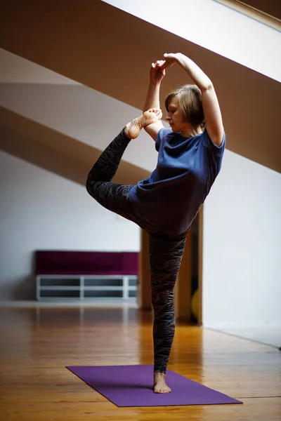 En idrottsman flicka gör otroliga yogaövningar i gymmet. — Stockfoto