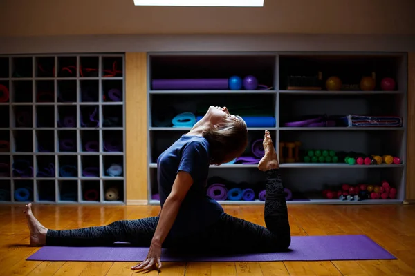 En kvinna gör yoga eller pilates övningar i gymmet — Stockfoto
