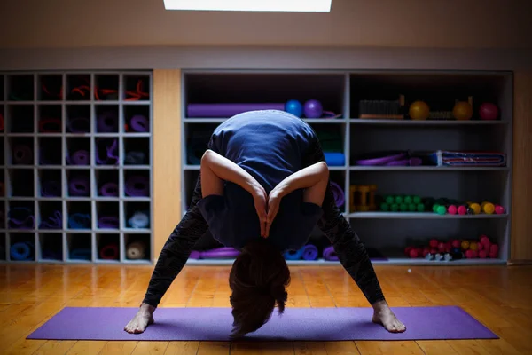 En idrottsman flicka gör otroliga yogaövningar i gymmet. — Stockfoto