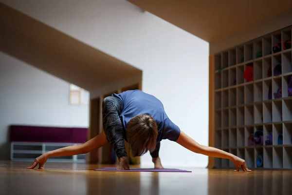 En idrottsman flicka gör otroliga yogaövningar i gymmet. — Stockfoto