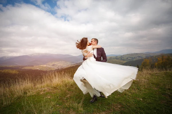 Liebespaar sind frisch vermählt in den Bergen. Stilvolle Braut mit einem Strauß küsst den Bräutigam. Liebe, Treue und Verschattungskonzept. Berg — Stockfoto