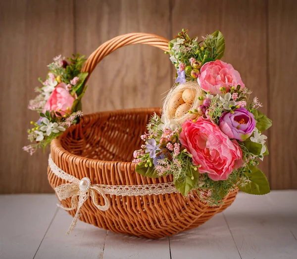 Feestelijke mand, versierd met bloemen op houten achtergrond. — Stockfoto