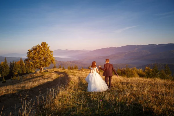 Mann und Frau haben gerade in den Bergen bei Sonnenuntergang geheiratet. — Stockfoto
