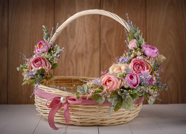 Корзина с цветами для празднования Пасхи на деревянном фоне — стоковое фото