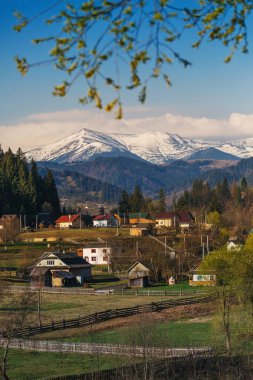 Mavi gökyüzü güzel karla kaplı dağlar. Dağ köyü ön planda