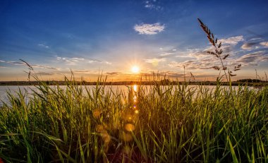 Göl kıyı çim üzerinde akşam günbatımı manzarası. Günbatımı Nehri.