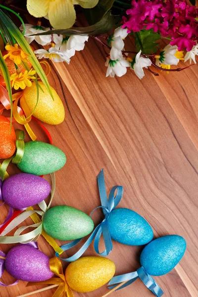 Easter flower arrangement and colorful eggs on wooden surface — Stock Photo, Image
