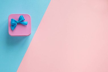 Mavi fiyonklu pembe hediye kutusunun basit kompozisyonu.