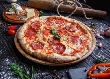 Sosisli ve domatesli Aromatik pizza fesleğenle süslenir.