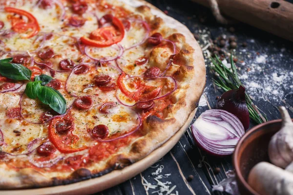 Pizza with sausages, ham, onions and tomatoes — Stock Photo, Image
