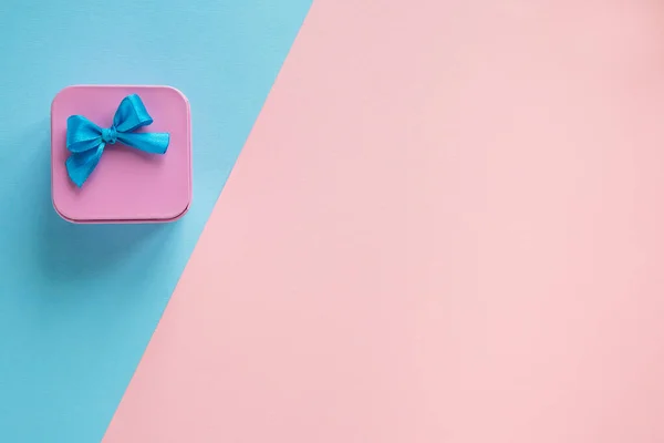 Eenvoudige compositie van roze geschenkdoos met een blauwe strik op een blauwe en — Stockfoto