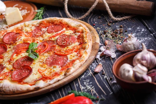 Pizza kolbásszal és paradicsommal fűszerek közelében — Stock Fotó