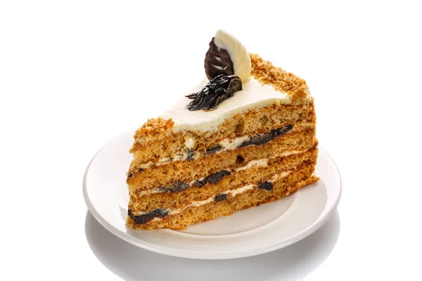 Um pedaço de bolo com mel e ameixas, destacado com um branco — Fotografia de Stock