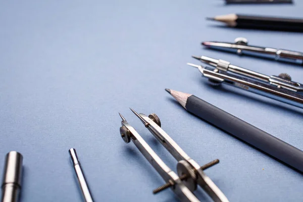 Compasses and pencils on a light blue background — Stock Photo, Image