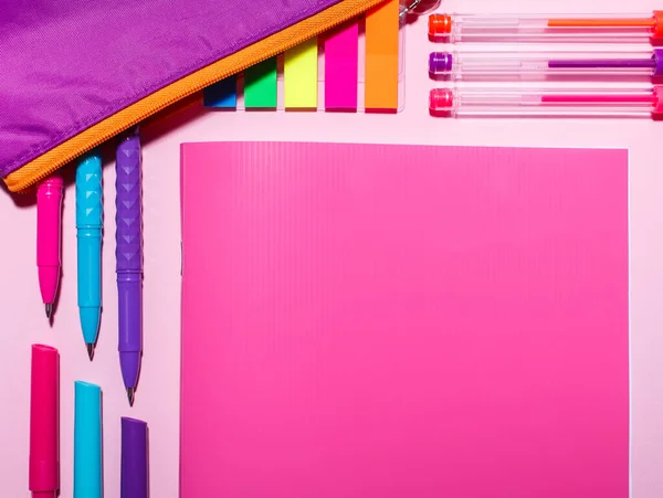 Op de roze tafel staat: een roze notitieboekje, kleurpennen en brik — Stockfoto