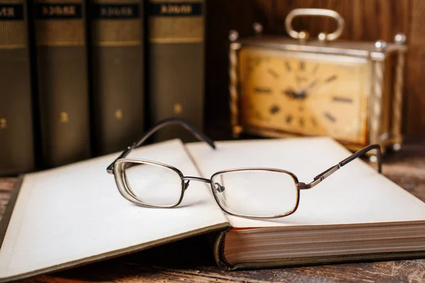 De bril ligt op het open boek in de bibliotheek — Stockfoto