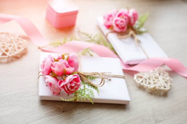 Beyaz kağıda sarılı hediye paketi ve ahşap bir arka planda ip yayı..