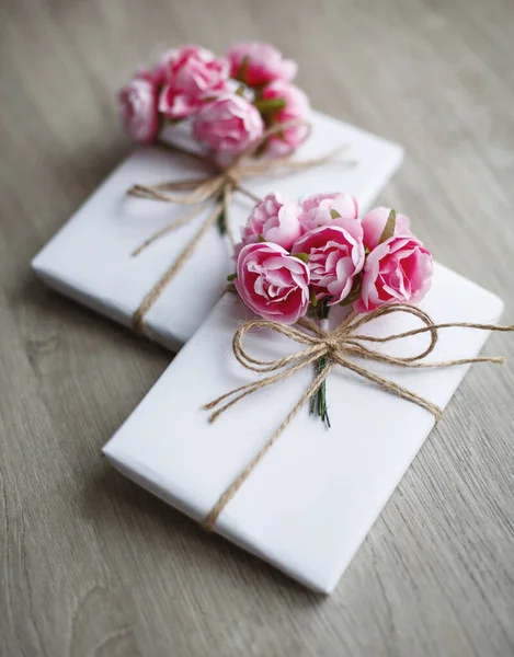 Caja de regalo artesanal de estilo natural en mesa de madera. Caja de regalo hecha a mano envuelta en papel blanco. Elementos decorativos florales . — Foto de Stock