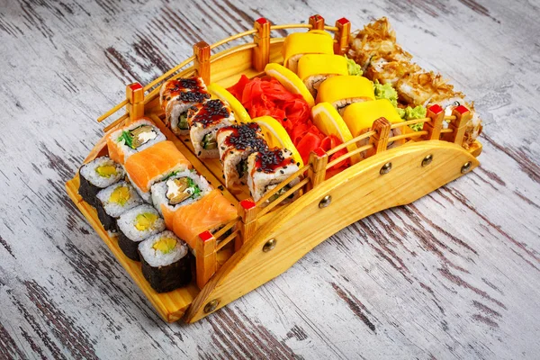 Különböző típusú sushi tekercsek fahídon — Stock Fotó