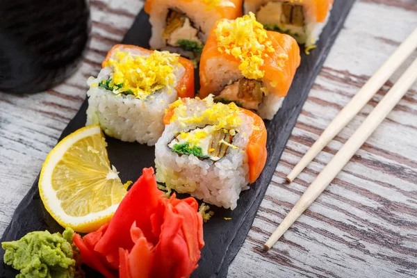 Szusit enni evőpálcikával. Sushi tekercs japán ételek étteremben. Kaliforniai sushi tekercs lazaccal. — Stock Fotó