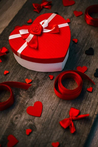Подарочная коробка в форме сердца с войлочными сердцами и атласным бантом на деревянной спинке — стоковое фото