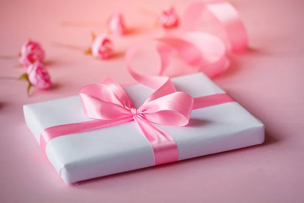 Scatola regalo avvolta in carta bianca con nastro rosa — Foto Stock