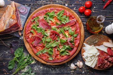 Etli, domatesli, peynirli, ahşap tabakta roka olan pizzanın üst görüntüsü..