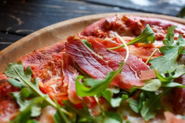 Etli pizza, domates, peynir, ahşap tabakta roka..