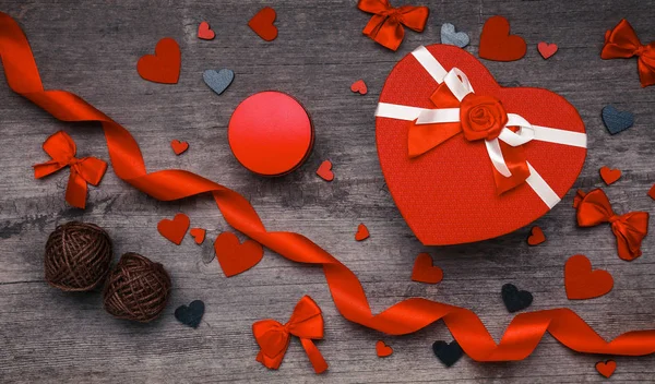 Caja de regalo en forma de corazón, corazones rojos, cintas, pajaritas sobre un fondo de madera . — Foto de Stock